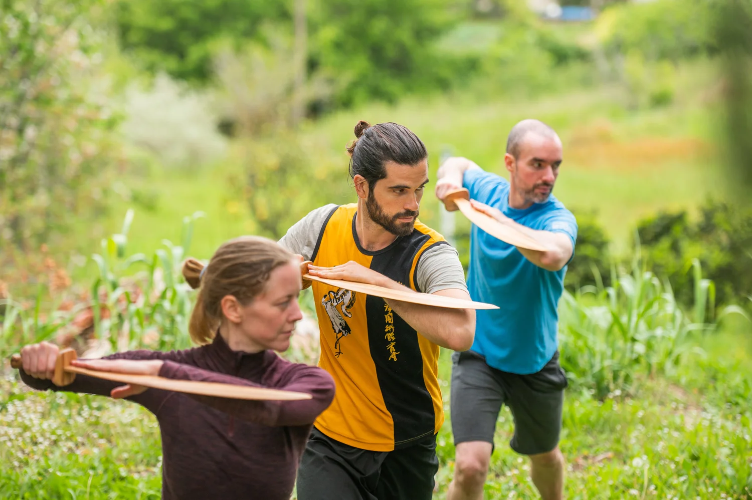 Students practising weapon forms together in a group class