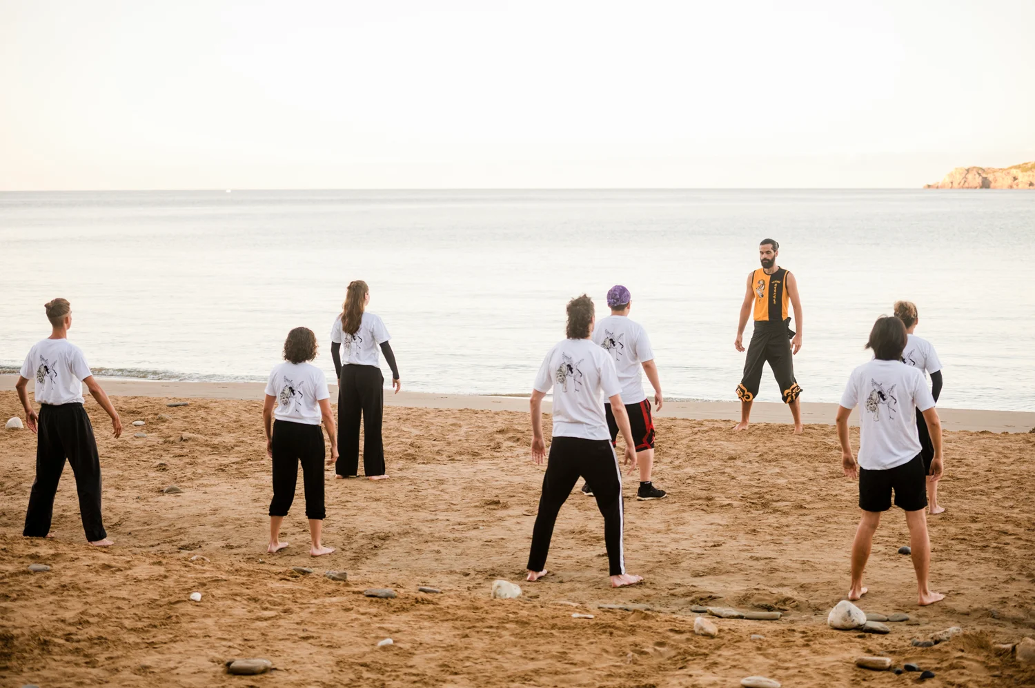 Students and instructor practising Kung Fu forms on the beach at sunrise in Corfu