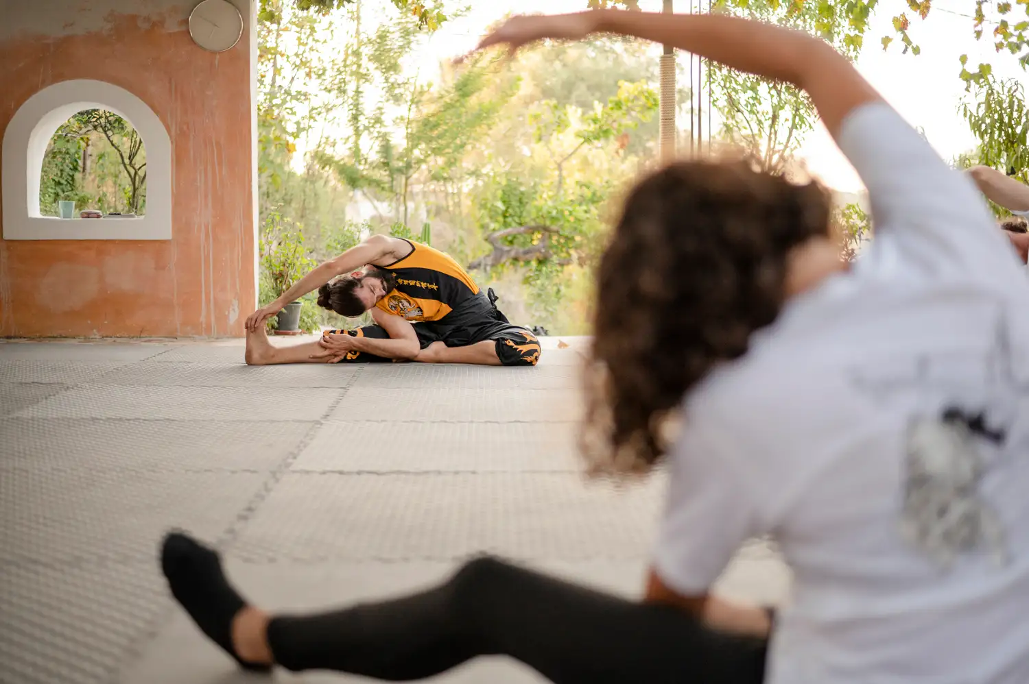 Thomas demonstrating a side stretch during a training session in Arillas, students following the exercise