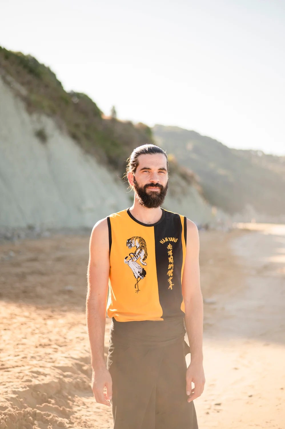 Thomas Croc standing on Arillas beach in his Nam Yang training top